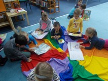 Dzieci oglądaja ksiązki siedząc na chuście animacyjnej