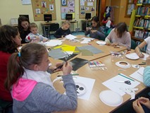 Dzieci siedzą przy stole wykonują prace plastyczne