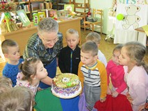 dzieci dmuchają świeczki na torcie i śpiewają 100 lat Misiowi