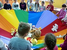 Dzieci trzymają chustę integracyjną z misiami w środku, za chwilę zaśpiewają misiom kołysankę