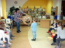 Bibliotekarka trzyma kartonową głowę misia - zadaniem dzieci jest nakarmić go zieloną cebulką