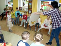 Bibliotekarka trzyma kartonową głowę misia - zadaniem dzieci jest nakarmić go zieloną cebulką