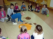 Dzieci układają figurkę misia z elementów po wyrzuceniu odpowiedniej  liczby oczek na kostce