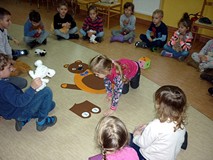 Dzieci układają figurkę misia z elementów po wyrzuceniu odpowiedniej  liczby oczek na kostce