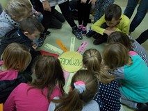 Grupa dzieci ustawiona nad pracą plastyczną