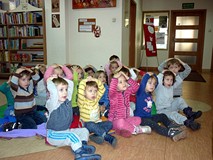 Dzieci siedzą na chuście i pokazują - naśladując prowadzącą - 