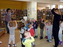 Bibliotekarka pokazuje jak otwiera się książka. Dzieci ją naśladują