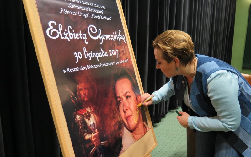 Elżbieta Cherezińska podpisuje plakat promujący spotkanie autorskie w Koszalińskiej...
