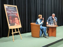 Elżbieta Cherezińska i prowadzący spotkanie Piotr Pawłowski obok plakatu promującego imprezę.