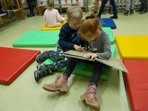 Dziewczynka i chłopiec wspólnie oglądają książkę Atlas Galaktyczny  