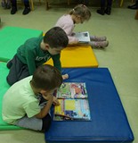 Chłopcy przeglądają gazetę sportową, a dziewczyna ogląda książkę