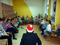 Dzieci siedzą na krzesełkach w kręgu. 