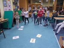 Dzieci tańcza wokół ilustracji rozłożonych na dywanie