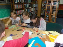 Trzy dziewczynki siedzą przy stole i wykonują prace plastyczne