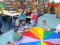 Bibliotekarka ogląda z dziećmi ksiązeczki