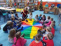 Biblotekarka pokazuje książkę dzieciom, które zgadują co jest na ilustracji