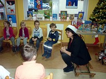 Dzieci siedzą na krzesełkach, bibliotekarkach siedzi na saneczkach i zadaje pytania CO DZIECI WIEDZĄ