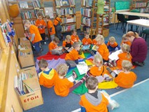 Dzieci z bibliotekarką siedzą na chuście i oglądają książki