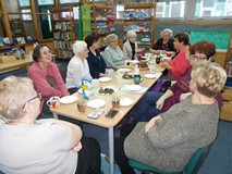 Panie siedzą wspólnie przy stole i rozmawiają