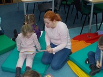 Bibliotekarka czyta dziewczynce książkę