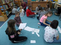 Dzieci pracują w grupie, siedząc na ziemi