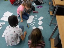 Dzieci układają z kształtów człowieka o trzech prach rąk i trzech parach nóg