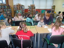 Dzieci wykonują pracę plastyczną, a bibliotekarka wspiera ich pracę