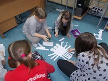 Trzy dziewczynki układają z kształtów potwora mitologicznego