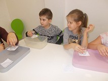 Chłopiec i dziewczynka pokazują wykonane przez siebie doświadczenia