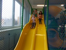 Dzieci zjeżdzają ze ślizgawki w sali zabaw