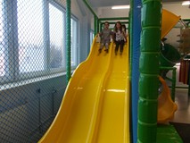 Dzieci zjeżdżaja ze zjeżdżalni w sali zabaw