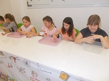 Kilkoro dziewcząt wykonuje przy stole eksperyment z wodą