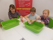 Troje dzieci wykonują eksperyment z wodą