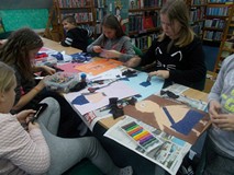 Dzieci siedzą przy stoliku i wykonują pracę plastyczną