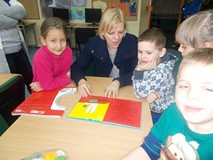 Czwroro dzieci słucha swojej nauczycielki która czyta im książki