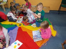 Dzieci siedzą na chuście i oglądają książeczki