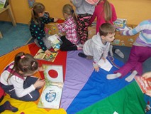 Dzieci siedzą na chuście i oglądają książki