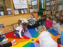 Dzieci słuchają bibliotekarki, która czyta książkę