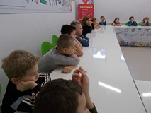 Dzieci siedzą przy stołach i obserwują doświadczenia