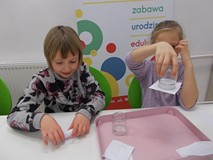 Dwie dziewczynki podczas wykonywania doświadczeń z wodą