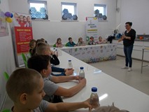 Dzieci siedza przy stołach i wykonuja doświadczenia z wodą