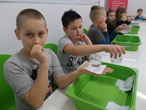 Dzieci siedząc przy stole podczas wykonywania doświadczenia z wodą