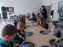 Dzieci siedzą przy stole, podczas prezentacji w Obserwatorium