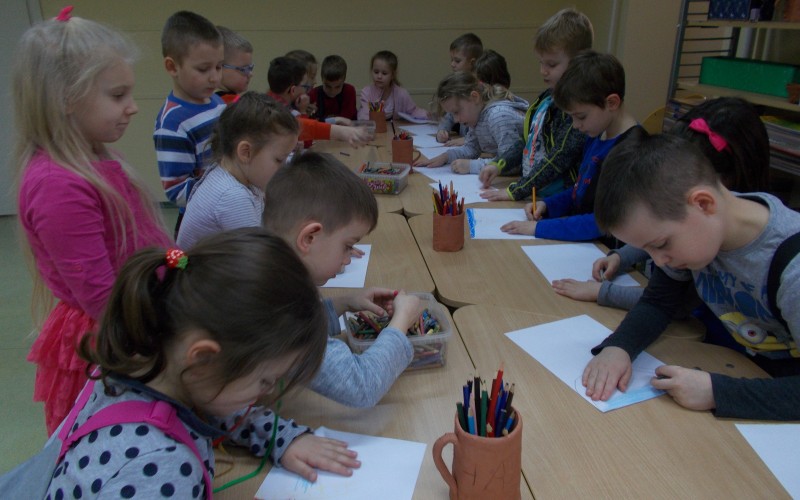 Grupa przedszkolaków przy stole zajęta rysowaniem