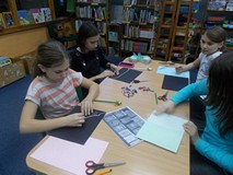 Czrtery dziewczynki siedzą przy stole i wykonują prace plastyczne