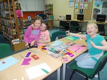 Trzy dziewczynki pozują do zdjęcia podczas pracy plastycznej