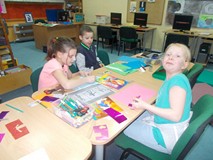 Toje dzieci siedzą przy stole i wykonują prace pladtyczne