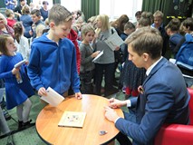 Jakub Skworz podpisuje książki po spotkaniu autorskim z dziećmi w Koszalińskiej Bibliotece Publiczne