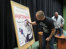 Łukasz Orbitowski podpisuje plakat promujący spotkanie