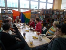 Panie i bibliotekarka siedzą przy stole i rozmawiają o książce